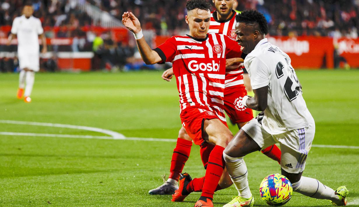 Pemain Real Madrid, Vinicius Junior, berebut bola dengan pemain Girona, Arnau Martinez, pada laga Liga Spanyol di Stadion Montilivi, Rabu (26/04/2023). (AP Photo/Joan Monfort)