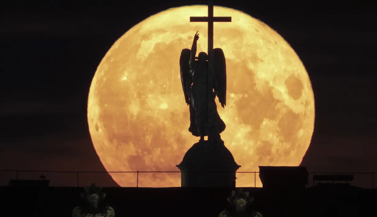 Supermoon terbit di belakang patung malaikat yang dipasang di atas Kolom Alexander di Alun-alun Istana di St. Petersburg, Rusia, Selasa, 1 Agustus 2023. (AP Photo/Dmitri Lovetsky)