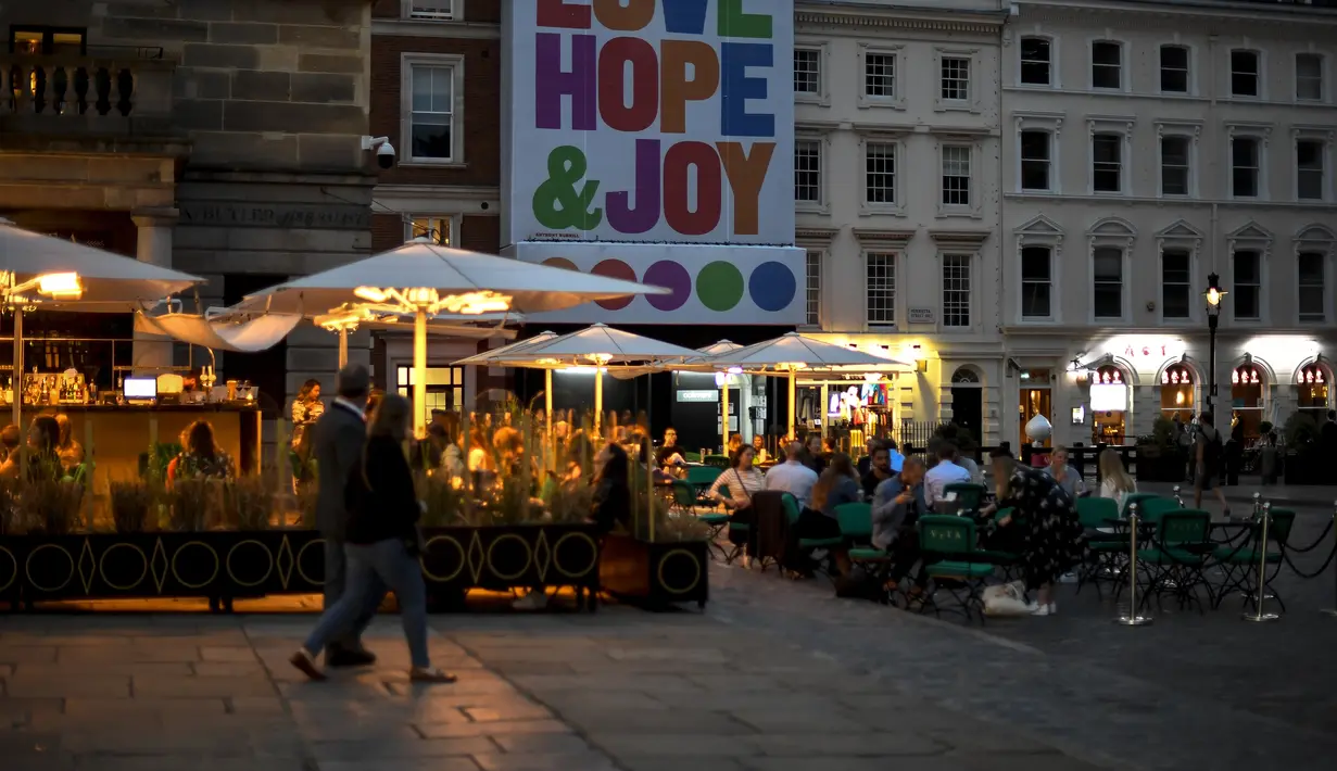 Orang-orang makan dan minum di Covent Garden, di London, Selasa (22/9/2020). Perdana Menteri Inggris, Boris Johnson, telah mengumumkan bahwa pub dan restoran tutup pada pukul 10 malam, karena lonjakan kasus virus corona di seluruh Inggris. (AP Photo / Alberto Pezzali)