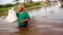 Seorang pria menerjang banjir yang melanda Perumahan Total Persada, Periuk, Kota Tangerang, Selasa (4/2/2020). Banjir akibat tanggul kali Ledug jebol membuat ratusan rumah di Total Persada terendam banjir hingga mencapai 3,5 meter. (merdeka.com/Arie Basuki)