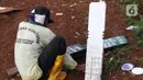 Petugas menyiapkan papan nisan jenazah yang akan dimakamkan dengan protokol COVID-19 di TPU Pondok Ranggon, Jakarta, Kamis (12/10/2020). Gubernur DKI Jakarta Anies Baswedan menganggarkan Rp254 miliar guna menambah lahan pemakaman jenazah dengan protokol Covid-19. (Liputan6.com/Helmi Fithriansyah)