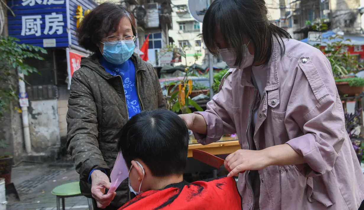 Seorang anak memangkas rambut di luar ruangan di Distrik Xiling, Kota Yichang, Provinsi Hubei, China, Jumat (20/3/2020). Aktivitas komersial warga Yichang berangsur normal sejak pertengahan Maret lalu. (Xinhua/Cheng Min)