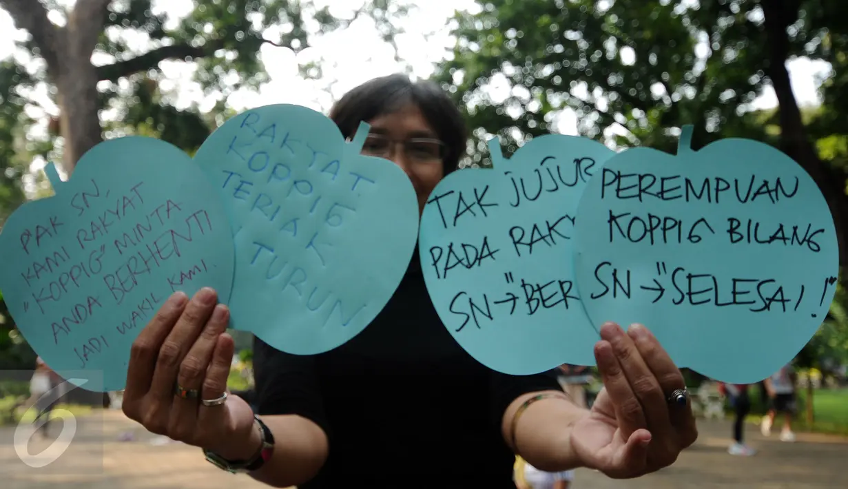 Salah satu perempuan pegiat antikorupsi menunjukkan tulisan saat aksi penyampaian pendapat usai berolahraga yoga di Taman Suropati, Jakarta, Minggu (6/12). Kegiatan ini juga bentuk peringatan Hari Anti korupsi. (Liputan6.com/Helmi Fithriansyah)