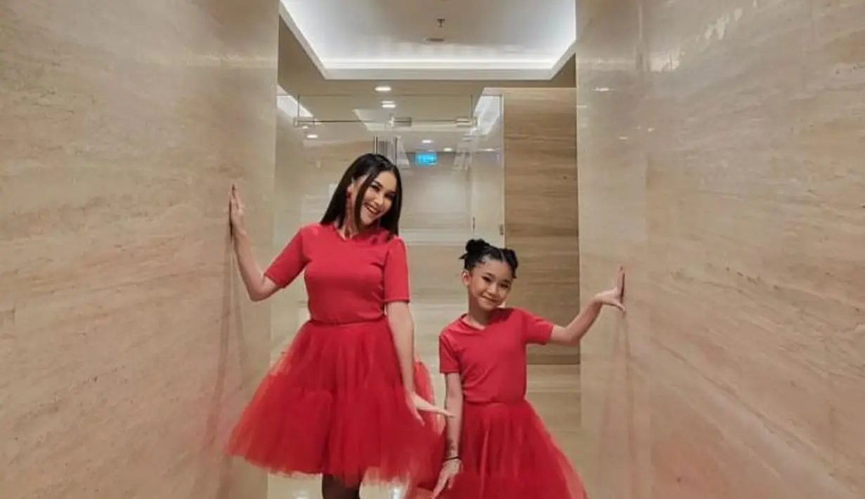 Ibu dan anak ini kembaran pakai dress tulle merah yang dipadukan sepatu boots hitam.