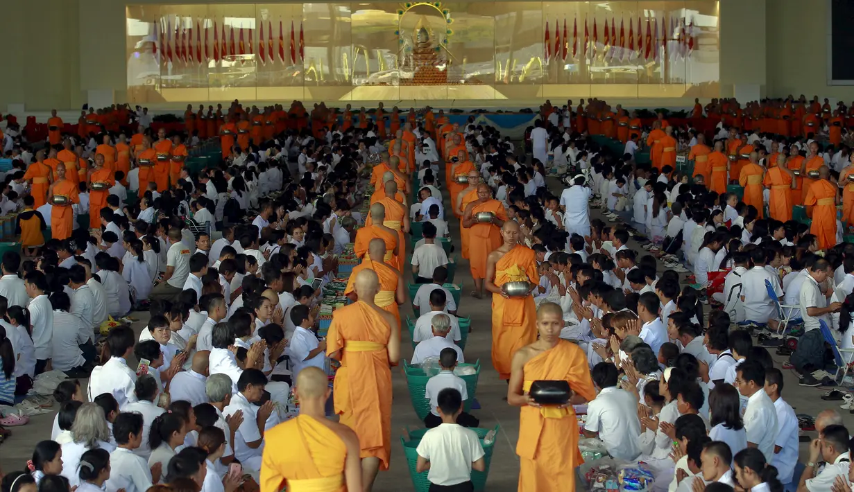 Sejumlah Biksu Buddha berjalan diantara umat Buddha yang sedang melakukan doa untuk mengumpulkan sedekah atau Pindapata dalam merayakan Hari Raya Waisak di Wat Dhammakaya Thailand, (1/6/2015). (REUTERS/Chaiwat Subprasom)