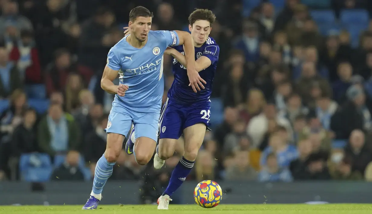 Bek Manchester City Ruben Dias berebut bola dengan penyerang Leeds United Daniel James dalam laga pekan ke-17 Liga Inggris di Etihad Stadium, Rabu (15/12/2021) dini hari WIB. Manchester City mencukur tamunya Leeds United tujuh gol tanpa balas. (AP Photo/Jon Super)