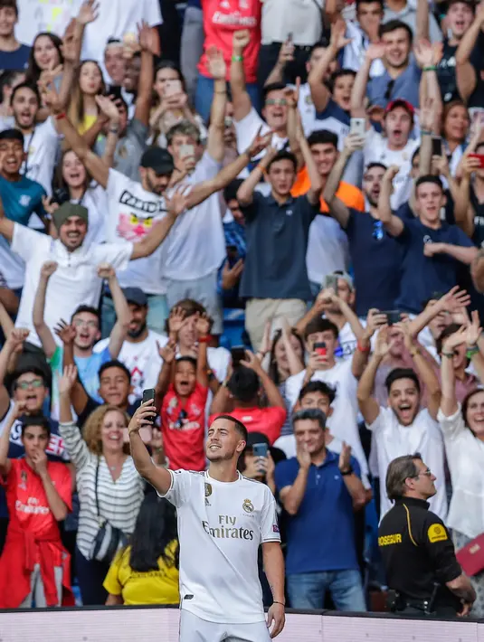 Pemain baru Real Madrid, Eden Hazard berselfie dengan fans saat diperkenalkan di stadion Santiago Bernabeu di Madrid, Spanyol (13/6/2019). Eden Hazard dibeli dari Chelsea senilai 100 juta euro. (AP Photo/Manu Fernandez)