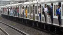 Penumpang berdiri pada pintu gerbong kereta yang terbuka saat mereka melakukan perjalanan dengan kereta lokal di Mumbai, India, Kamis (8/9/2022). India merupakan salah satu negara dengan penduduk terbanyak di dunia sehingga kereta di negara tersebut berukuran panjang dan lebar. (Indranil MUKHERJEE/AFP)