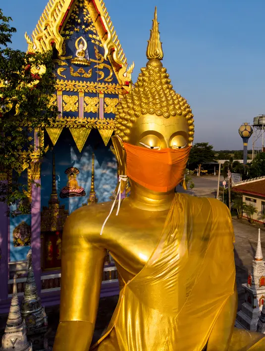 Sebuah foto udara menunjukkan masker diletakkan pada wajah patung Buddha raksasa di kuil Wat Nithet Rat Pradit di Pathum Thani di luar Bangkok, Thailand, 12 Mei 2020. Pemasangan masker tersebut sebagai tanggapan terhadap penyebaran pandemi Covid-19. (Photo by Mladen ANTONOV / AFP)