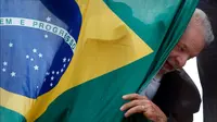 Mantan presiden Brasil (2003-2010) dan kandidat presiden dari Partai Pekerja (PT) berhaluan kiri, Luiz Inacio Lula da Silva, muncul di belakang bendera nasional Brasil selama kampanye di Sao Mateus, Negara Bagian Sao Paulo, Brasil, Senin (17/10/2022). Lula da Silva dan presiden Jair Bolsonaro akan menghadapi putaran kedua pemilihan presiden pada 30 Oktober, dengan ekspektasi persaingan ketat mendorong kedua belah pihak untuk mengintensifkan kampanye pemilihan. (Miguel SCHINCARIOL / AFP)