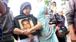 Salah satu anak almarhum Yani Libels membawa foto pria bernama asli Yanni Rusiana Djunaedi itu saat pemakaman di TPU Tanah Kusir, Jakarta, Kamis (26/3/2015).  (Liputan6.com/Panji Diksana)
