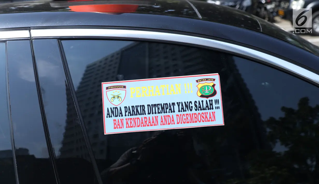Stiker sanksi tertempel di mobil yang parkir di halaman Polda Metro Jaya, Senin (19/11). Polda Metro Jaya menerapkan sanksi penggembosan dan penempelan stiker bagi kendaraan yang parkir sembarangan di halaman Polda Metro. (Liputan6.com/Helmi Fithriansyah)