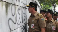 Gubernur DKI Jakarta Basuki T Purnama melihat kondisi tembok di sekitar kawasan pasar Tanah Abang, Jakarta, Rabu (15/4). Ahok berjalan kaki dari Stasiun Tanah Abang menuju Pasar Blok G untuk mengecek kondisi trotoar jalan. (Liputan6.com/Herman Zakharia)