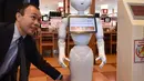 Karyawan dari pengembang robot humanoid Pepper mendemonstrasikan robotnya saat press preview di Saitama, Jepang (2/2). Robot tersebut dapat melayani pelanggan dan membuka pintu masuk ke meja resepsionis. (AFP/Kazuhiro Nogi)