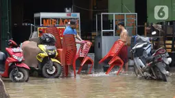 Pedagang membersihkan bangku di Kawasan pertokoan Jalan KH Hasyim Ashari, Ciledug, Tangerang, Kamis (2/1/2020). Banjir yang melanda Ciledug dan sekitarnya membuat aktivitas perekonomian di kawasan tersebut lumpuh sementara. (Liputan6.com/Angga Yuniar)
