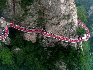 Sebuah acara perjamuan yang diadakan di sepanjang tepi tebing di Laojun Mountain provinsi Henan, bagian tengah China. Wisatawan menikmati berbagai suguhan makanan di jalanan selebar enam kaki yang menempel pada tebing setinggi 2.000 meter. (AFP)
