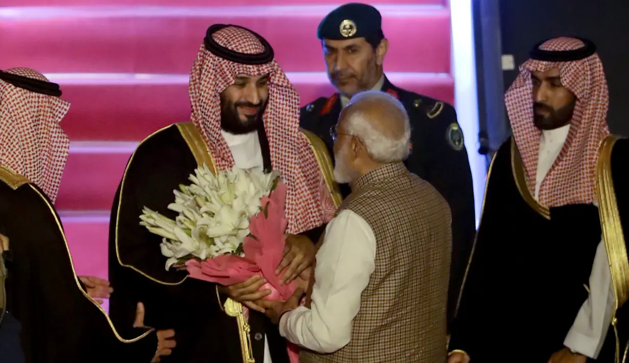 PM India, Narendra Modi memberikan bunga saat menyambut Putra Mahkota Arab Saudi Pangeran Mohammed bin Salman di bandara New Delhi, Selasa (19/2). Modi memutuskan  melanggar protokoler untuk secara pribadi menyambut Putra Mahkota Saudi. (AP/Manish Swarup)