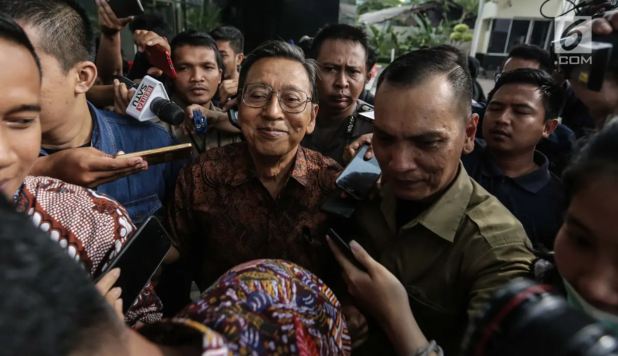 Mantan Wakil presiden RI Boediono berusaha menghindari kerumunan wartawan seusai menjalani pemeriksaan di gedung KPK, Jakarta, Kamis (28/12). Boediono irit bicara setelah diperiksa KPK terkait kasus BLBI selama hampir 6 jam. (Liputan6.com/Faizal Fanani)