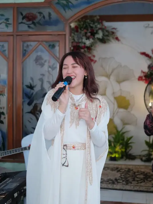 Gaya santun Happy Asmara manggung pakai kaftan. Penampilannya manis mengenakan kaftan putih dengan bordir jahitan emas dan merah yang mempermewah nuansa penampilannya secara keseluruhan. [Foto: Instagram/happy_asmara77]