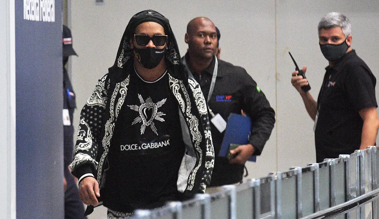 Mantan pemain timnas Brasil, Ronaldinho tiba di bandara El Galeao di Rio de Janeiro, setelah menjalani tahanan rumah di Paraguay, Selasa (25/8/2020). Ronaldinho menghirup udara bebas setelah lima bulan menjadi tahanan rumah karena memasuki Paraguay dengan paspor palsu. (Carl DE SOUZA/AFP)