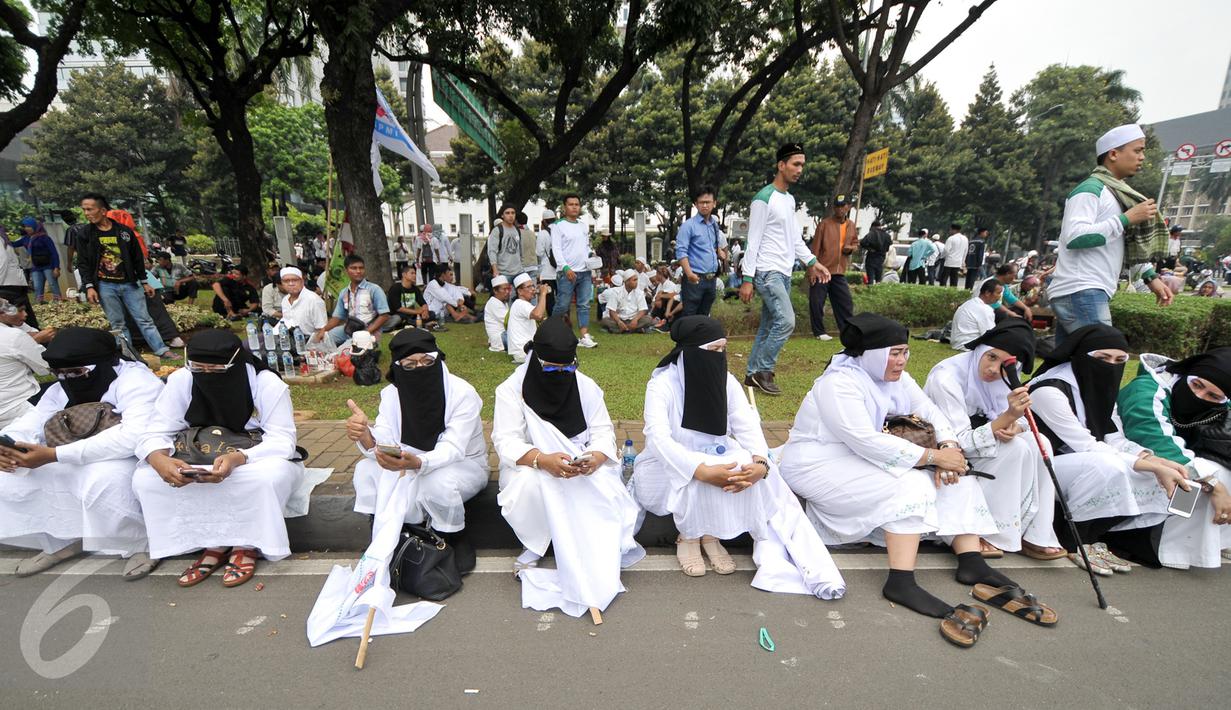 Sejumlah demonstran perempuan beristirahat di pinggir taman Jalan Medan Merdeka Selatan, Jumat (4/11). Ratusan ribu massa aksi damai melakukan aksi menuntut penegakan hukum kasus dugaan penistaan agama. (Liputan6.com/Yoppy Renato)