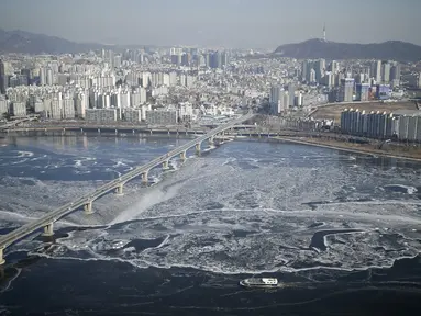 Sebuah kapal penumpang (bawah) menyeberangi aliran es di Sungai Han yang membeku di Seoul, Korea Selatan, Senin (25/1). Sungai Han membeku akibat suhu di Korea yang kini mencapai minus dol derajat Celsius. (REUTERS/Kim Hong - Ji)