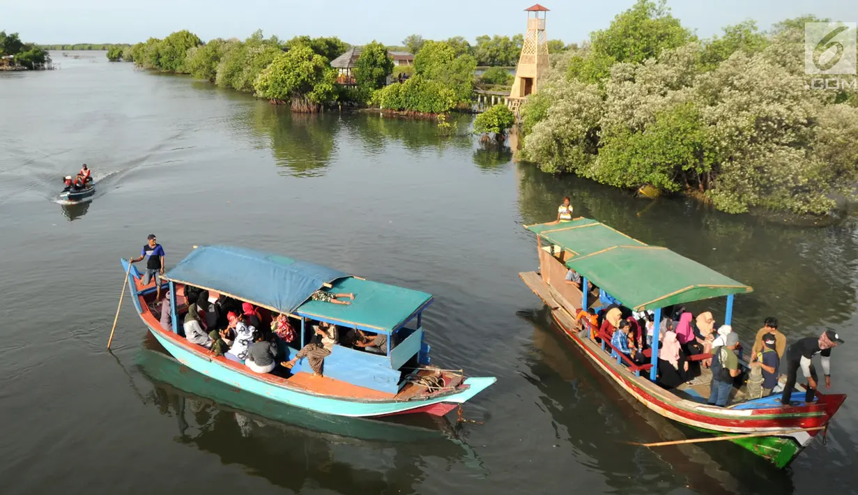 Perahu wisata melintasi kerumunan wisatawan yang berjalan di atas Jembatan Cinta di Wisata Mangrove, Tarumajaya, Bekasi, Minggu (30/12). Wisata tersebut awalnya merupakan Pusat Restorasi dan Pembelajaran Mangrove (PRPM) Bekasi. (merdeka.com/Arie Basuki)