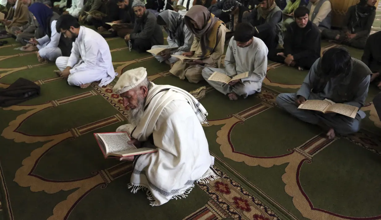 Umat muslim membaca Al-Quran selama melaksanakan salat berjemaah pada hari pertama bulan Ramadan di sebuah masjid di Kabul, Afghanistan, Jumat (24/4/2020). Mereka melaksanakan salat di tengah kekhawatiran akan penularan virus corona COVID-19. (AP Photo/Rahmat Gul)