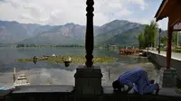 Seorang pria Muslim Kashmir melaksanakan salat di tepi Danau Dal pada hari kedua Ramadan selama penguncian nasional untuk mengendalikan penyebaran virus corona Covid-19, di Srinagar, Kashmir yang dikuasai India, (26/4/2020). (AP Photo/Mukhtar Khan)