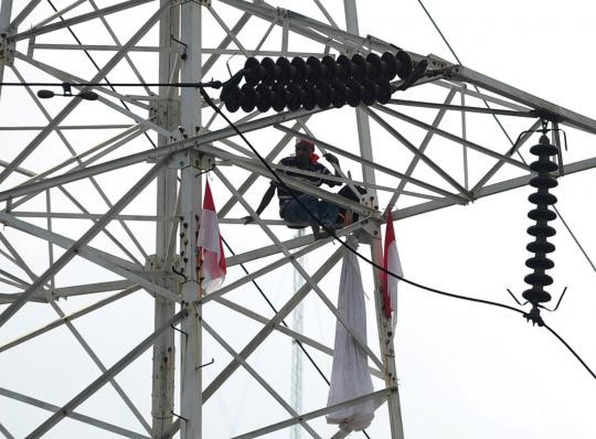 Pria berpakaian pocong di atas tower SUTET