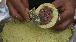 Seorang pedagang Palestina menyiapkan falafel diisi dengan bawang, sumac dan cabai, di restoran lokal di kota Hebron di Tepi Barat yang diduduki, Minggu (18/4/2021). Falafel adalah sebuah makanan Timur Tengah yang pada bulan Ramadhan, sering dimakan sebagai hidangan buka puasa. (HAZEM BADER/AFP)