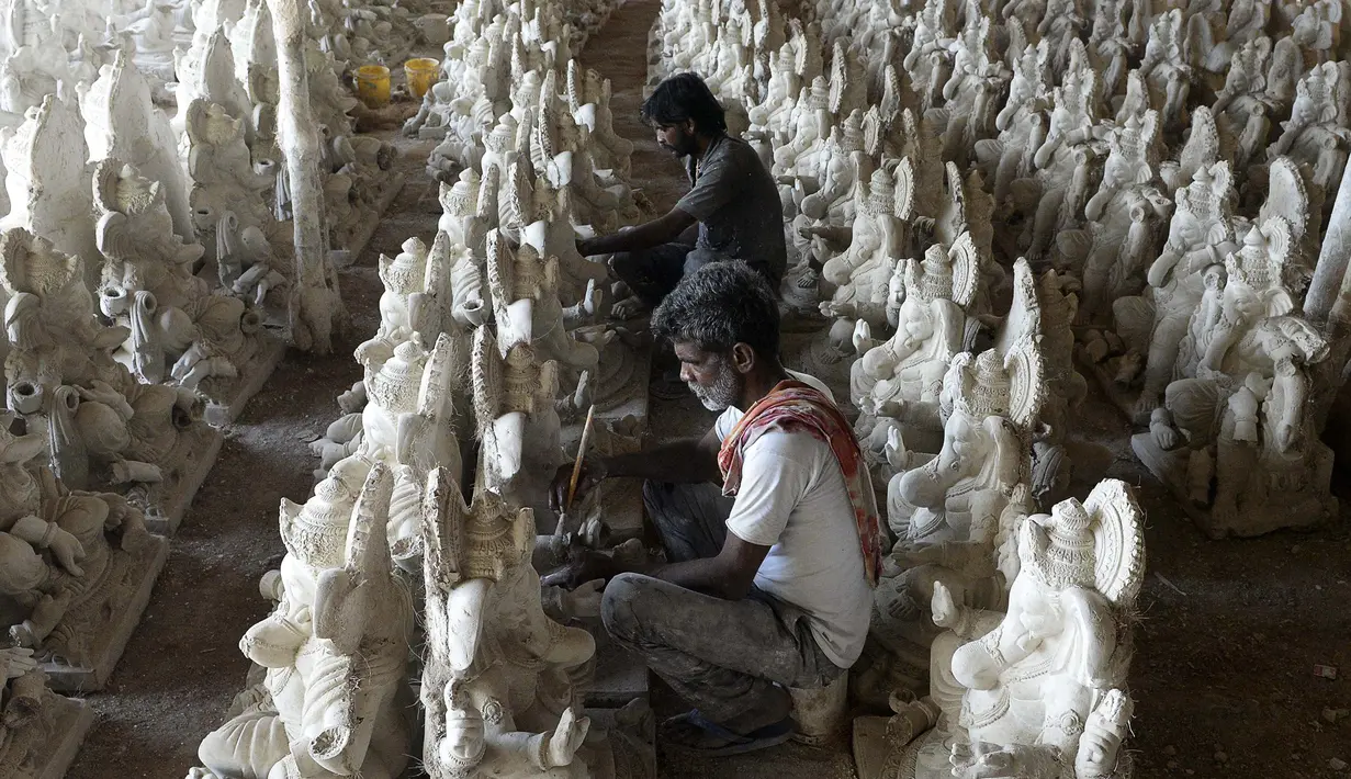 Para perajin menyelesaikan pembuatan patung Dewa Ganesha di sebuah bengkel di pinggiran Hyderabad, India, Senin (29/6/2020). Patung Dewa Ganesha banyak ditemukan di berbagai penjuru India termasuk Nepal, Tibet, dan Asia Tenggara. (NOAH SEELAM/AFP)