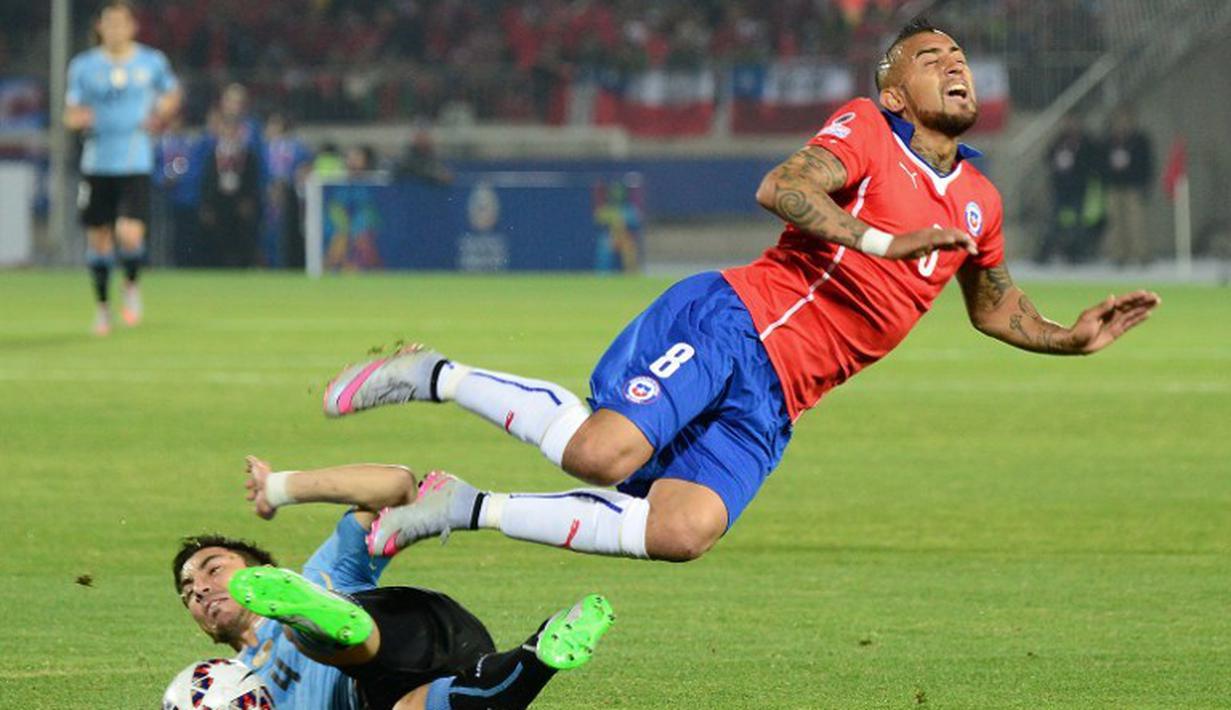 Gelandang Cile, Arturo Vidal (kanan) dijatuhkan pemain Uruguay, Jorge Fucile. (AFP PHOTO/MARTIN BERNETTI)
