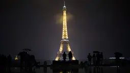 Pengunjung berkumpul di alun-alun Trocadero sebelum lampu Menara Eiffel dipadamkan di Paris, Senin (2/10). Lampu di menara yang menjadi ikon Negara Prancis ini akan dimatikan sebagai penghormatan kepada korban penembakan di Las Vegas. (AP/Kamil Zihnioglu)