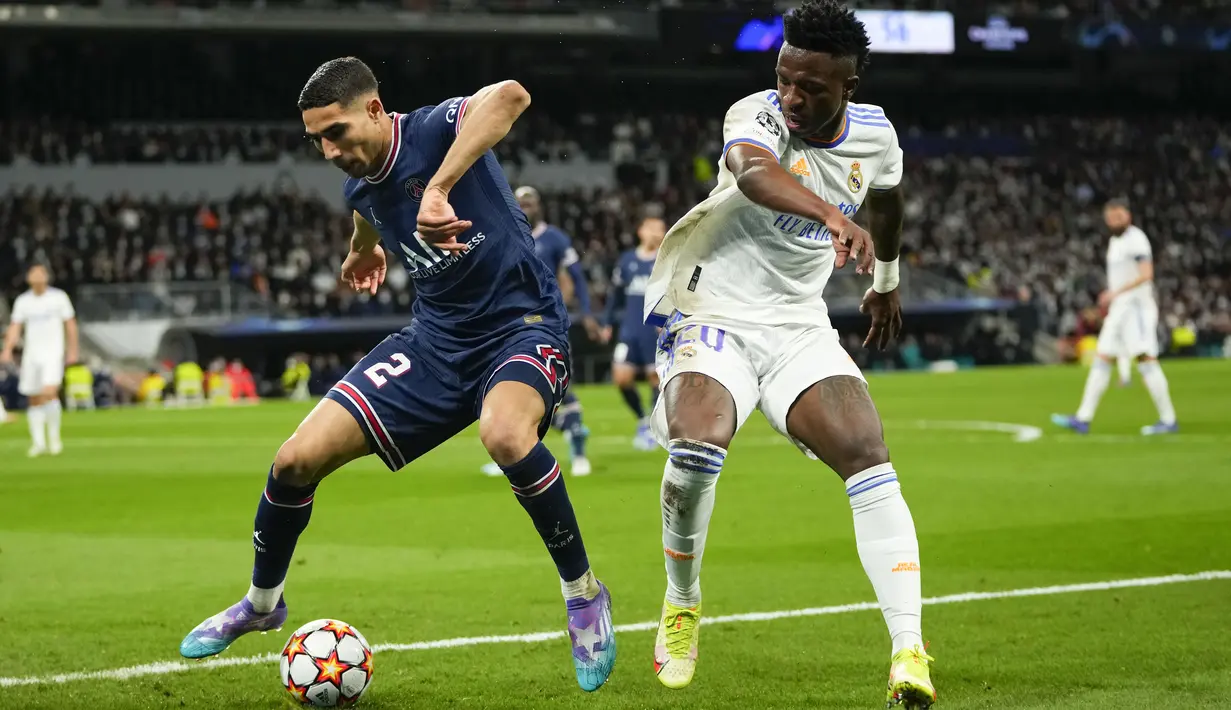 Bek Paris Saint-Germain (PSG) Achraf Hakimi berebut bola dengan penyerang Real Madrid Vinicius Junior pada leg kedua 16 besar Liga Champions di Santiago Bernabeu, Kamis (10/3/2022) dini hari WIB. Real Madrid secara dramatis sukses menyingkirkan PSG setelah menang 3-1. (AP Photo/Manu Fernandez)