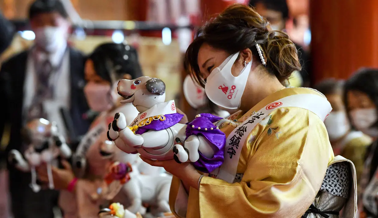Pemilik robot peliharaan Sony Aibo mengambil bagian dalam upacara doa untuk merayakan ulang tahun ketiga Aibo dan berharap kesehatan yang baik pada masa depan di Kuil Kanda, Tokyo, Jepang, Jumat (12/11/2021). (Kazuhiro NOGI/AFP)