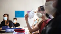 Siswa kelas sebelas dengan masker duduk di ruang kelas sekolah menengah Phoenix di Dortmund, Jerman barat, Rabu (12/8/2020). Para siswa di negara bagian Jerman, North Rhine-Westphalia, harus mengenakan masker setiap waktu ketika mereka kembali ke sekolah pada Rabu ini. (Ina FASSBENDER/AFP)