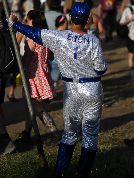 Seorang pengunjung festival mengenakan pakaian berkilauan bertuliskan "Elton 1" menghadiri hari pertama festival Glastonbury di desa Pilton, di Somerset, barat daya Inggris, pada 21 Juni 2023. Festival berlangsung dari 21 Juni hingga 26 Juni. (Photo by Oli SCARFF / AFP)