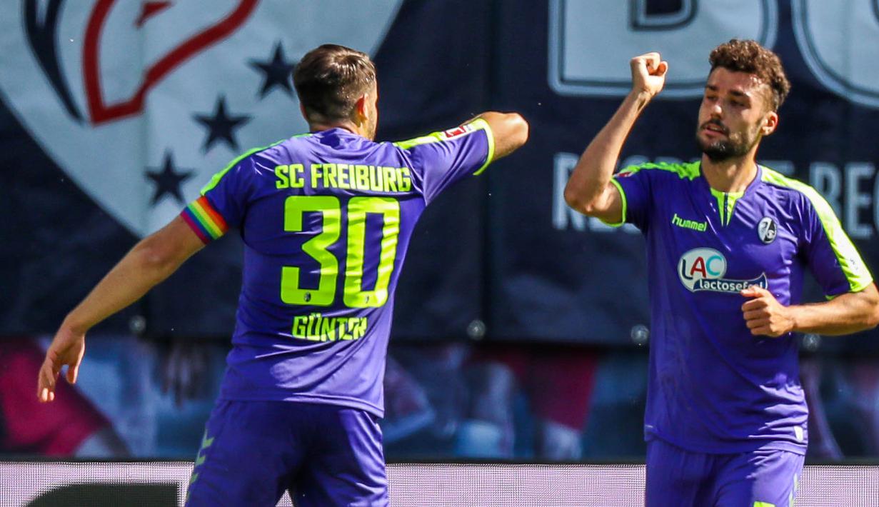 Pemain Freiburg, Manuel Gulde dan Christian Guenter merayakan gol yang dicetak ke gawang RB Leipzig pada laga Bundesliga di Leipzig, Sabtu (16/5/2020). Pandemi COVID-19 membuat pemain melakukan selebrasi jaga jarak. (AFP/Jan Woitas)