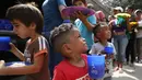 Anak-anak pengungsi Venezuela mengantre makanan di tempat penampungan Divina Providencia, La Parada, Cucuta, Kolombia, Senin (18/2). Makanan terdiri dari kacang-kacangan, daging bologna, nasi, dan sepotong pisang. (AP Photo/Fernando Vergara)
