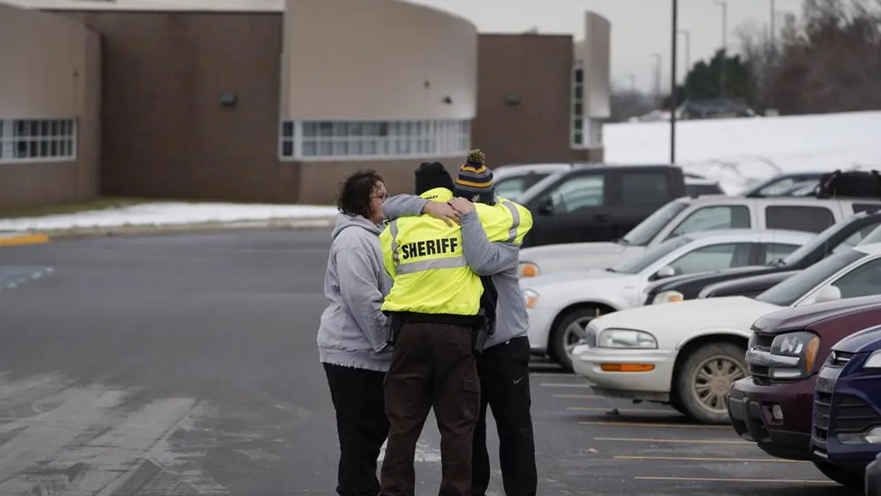Seorang sheriff memeluk keluarga murid sekolah SMA Oxford yang menjadi lokasi penembakan.