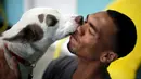 Pengunjung dijilat wajahnya oleh anjing saat pembukaan Dog Cafe coffee shop di Los Angeles, AS (7/4). Dog Cafe resmi menjadi kafe pertama di Los Angeles yang menawarkan pengunjung untuk dapat mengadopsi anjing di kafe tersebut. (REUTERS/Lucy Nicholson)