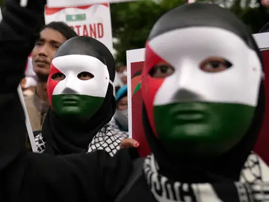 Para pengunjuk rasa yang mengenakan topeng dengan warna bendera Palestina memegang poster dalam aksi unjuk rasa untuk mendukung Palestina di luar Kedutaan Besar Amerika Serikat di Jakarta, Sabtu 13 Januari 2024. (AP Photo/Dita Alangkara)