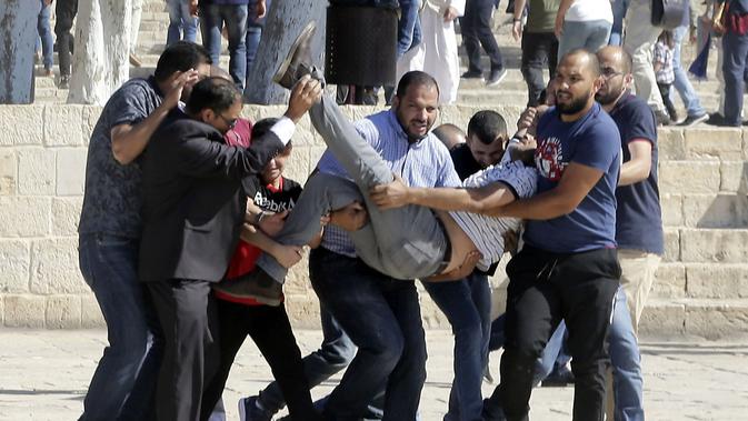 Sejumlah warga Palestina membawa seorang pria yang terluka saat bentrok dengan polisi Israel kompleks masjid al-Aqsa di Yerusalem (11/8/2019). Perayaan Idul Adha hari ini juga bertepatan dengan hari libur umat Yahudi yang dikenal dengan Tisha B'av. (AP Photo/Mahmoud Illean)