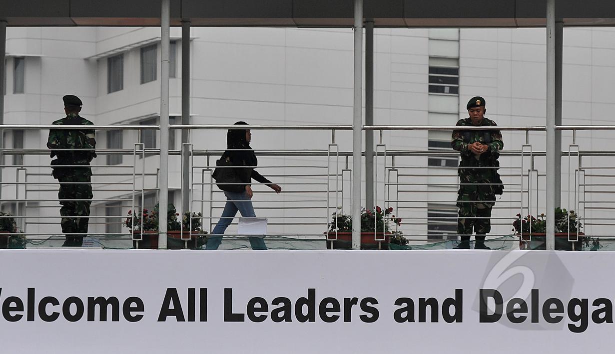 Warga melintas di jembatan penyeberangan orang (JPO) kawasan Bundaran HI Jakarta,  yang dijaga petugas keamanan, Sabtu (18/4/2015). Sterilisasi dilakukan di tempat-tempat umum yang dilalui peserta Konferensi Asia Afrika (KAA). (Liputan6.com/Johan Tallo)
