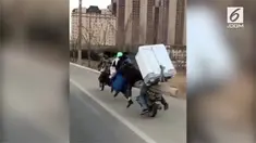 Sepeda motor berbentuk tak biasa mengangkut 7 anggota keluarga dan sebuah lemari es. Kendaraan itu melaju di jalanan Kota Chong Qing.
