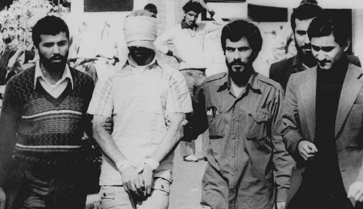 Seorang sandera dibawa saat kelompok radikal menyerbu Kedutaan Besar AS di Teheran, Iran, 9 November 1979. Melalui referendum nasional, Iran menjadi Republik Islam pada 1 April 1979. (AP Photo, File)