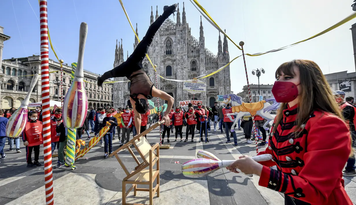 Seniman sirkus tampil di depan katedral gothic Duomo selama demonstrasi oleh pekerja sirkus di Milan, Italia utara (26/3/2021). Mereka menuntut lebih banyak dukungan dari pemerintah Italia karena kegiatan mereka ditutup sejak dimulainya wabah COVID-19. (Claudio Furlan/LaPresse via AP)