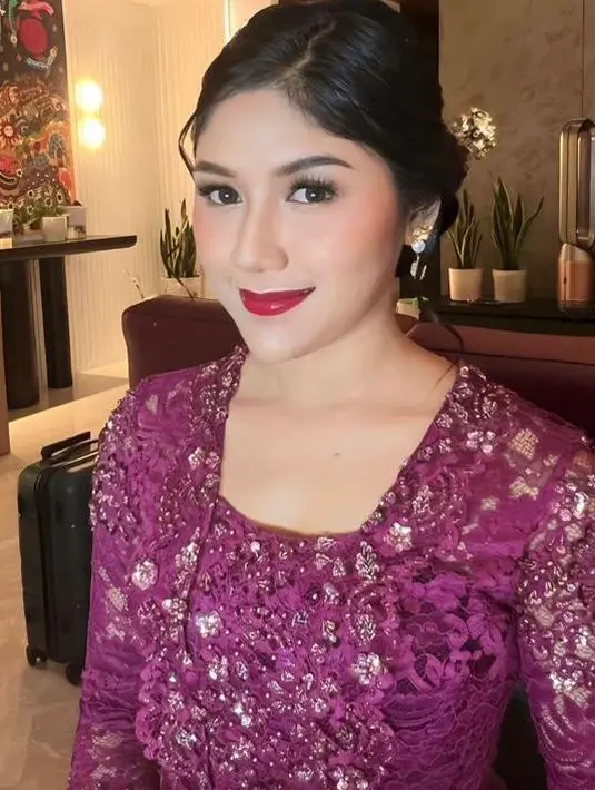 Wajahnya dipulas makeup bold oleh  Aulia Neosevituri. Sang Mua tampak mengaplikasikan eyeshadow coklat, blush on coral, dan lipgloss magenta yang senada dengan kebayanya pada bibirnya, [@erinagudono@angeliarzky/@sarahpdp]