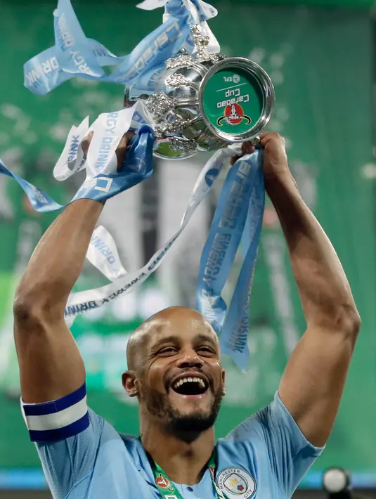 Bek Manchester City Vincent Kompany mengangkat trofi setelah memenangkan pertandingan final Piala Liga Inggris melawan Chelsea di stadion Wembley, London, Minggu (24/2). Manchester City Chelsea lewat drama adu penalti 4-3. (AP/ Tim Ireland)